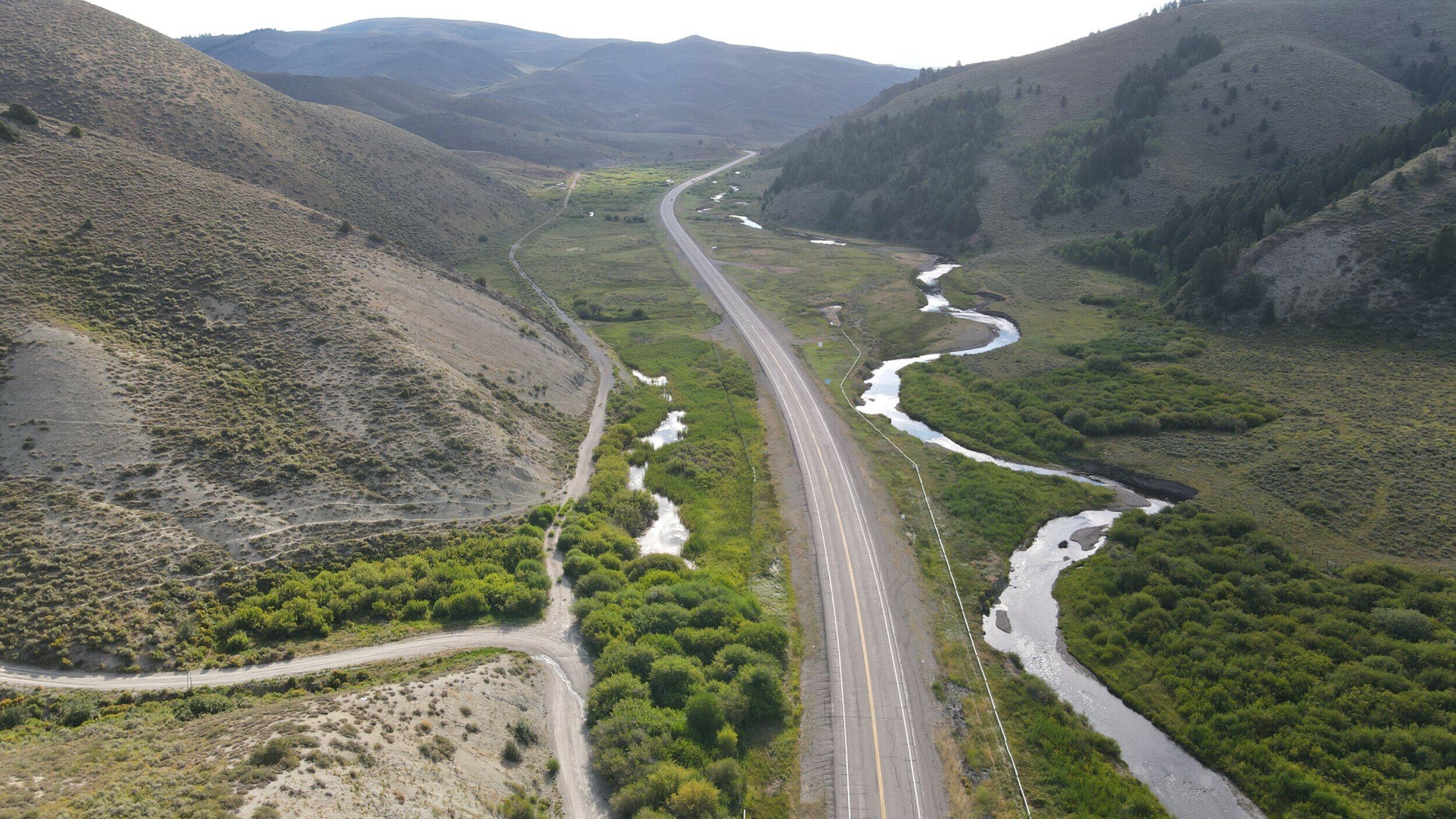 Aerial view of Wyoming Highway 89 meandering beside a serpentine river.