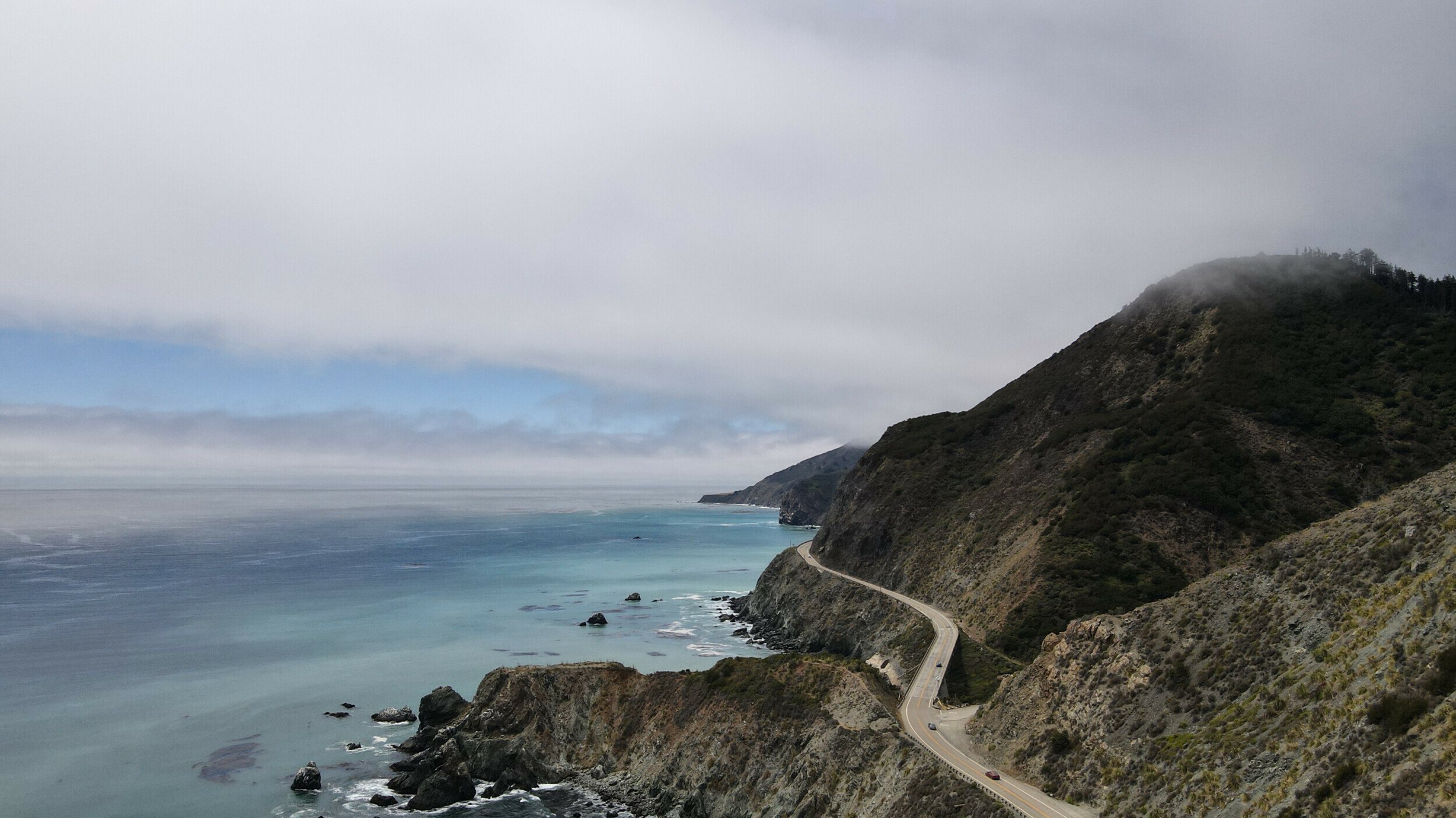 Aerial view of a winding road along the rugged coast near Limekiln State Park, California