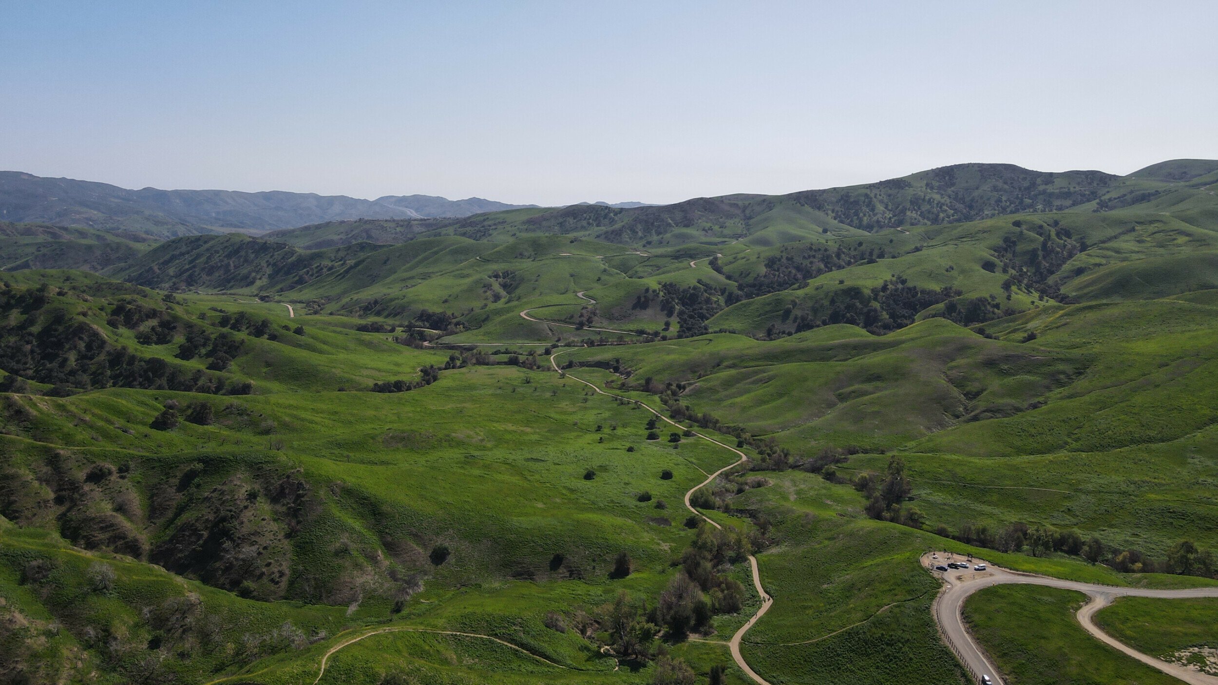 Aerial view of Chino Hills State Park showcasing lush green hills and a winding road taken by DJI Mavic Air 2 drone.