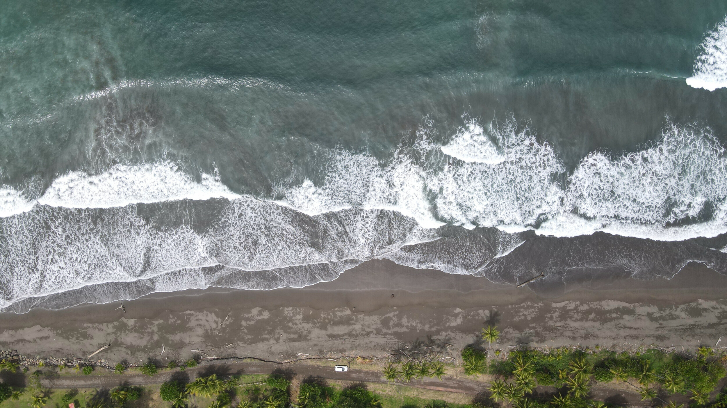 Aerial view of Palo Seco Beach's unique dark sands and lush palm fringe, Puntarenas Province, Costa Rica.