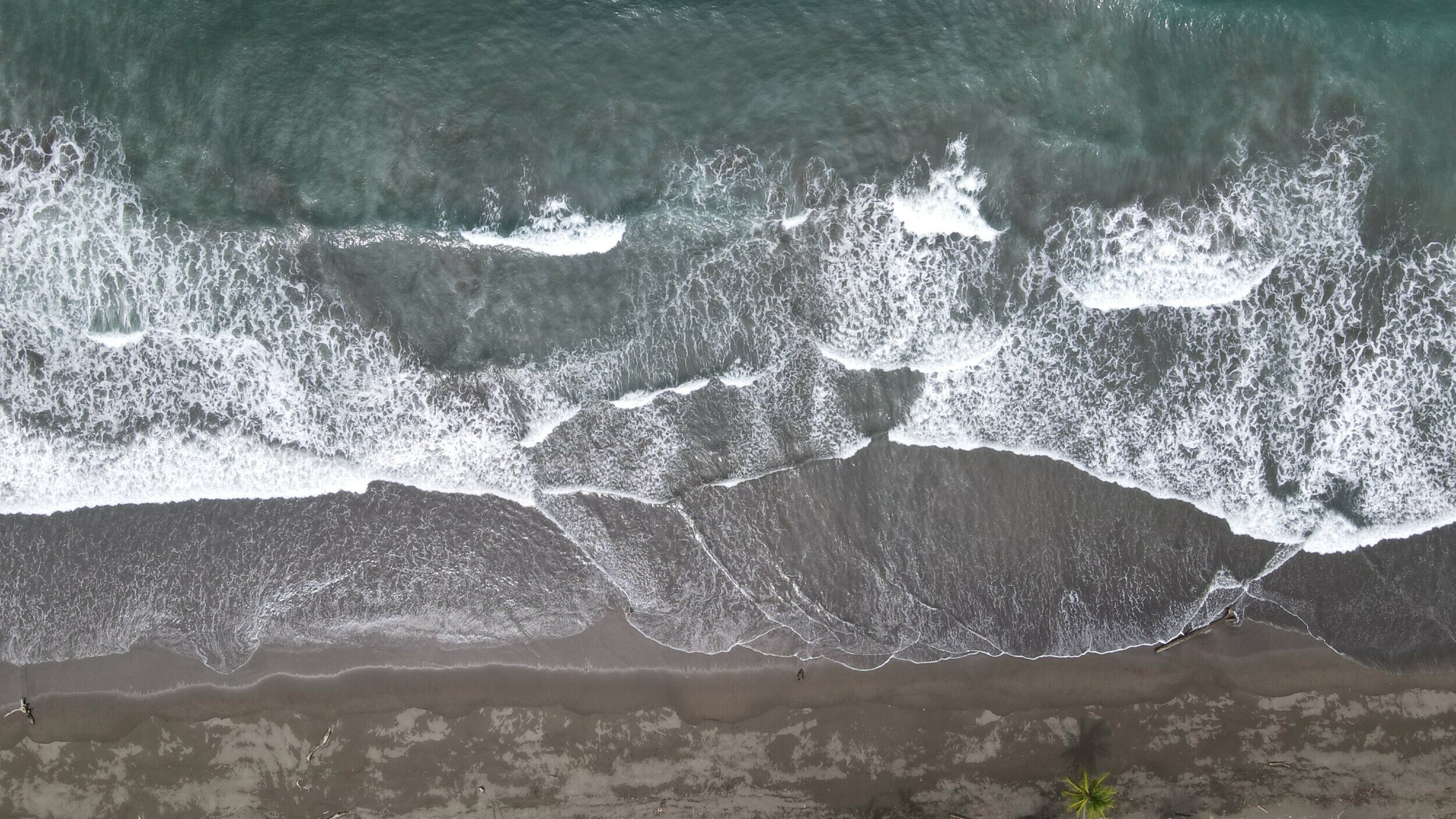 Aerial photo capturing the tranquil waves and deserted sands of Palo Seco Beach in Costa Rica, taken by DJI Mavic Air 2 drone
